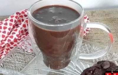Foto da receita de Chocolate Quente. Observa-se uma xícara branca transparente com a bebida dentro, sobre um pires transparente de vidro. Foto da receita de Chocolate Quente. Observa-se uma xícara branca transparente com a bebida dentro, sobre um pires transparente de vidro.
