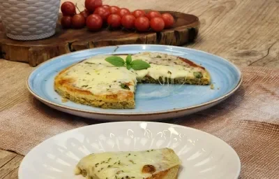 Fotografía en tonos marrones con un plato azul en el centro. Sobre el plato hay una pizza de avena con queso mozzarella y orégano.