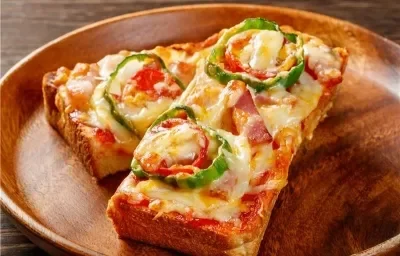 Fotografía de una pizza con queso fundido y tomate, cortada por la mitad, con la otra mitad encima de la primera. Las mitades están sobre un plato de madera redondo y poco profundo.