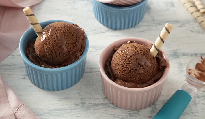 Foto de la receta de Helado de MOÇA con Nescau. Se pueden ver dos botes individuales, uno rosa y otro azul, uno con cada bola de helado. Cada bote tiene una barra de oblea.